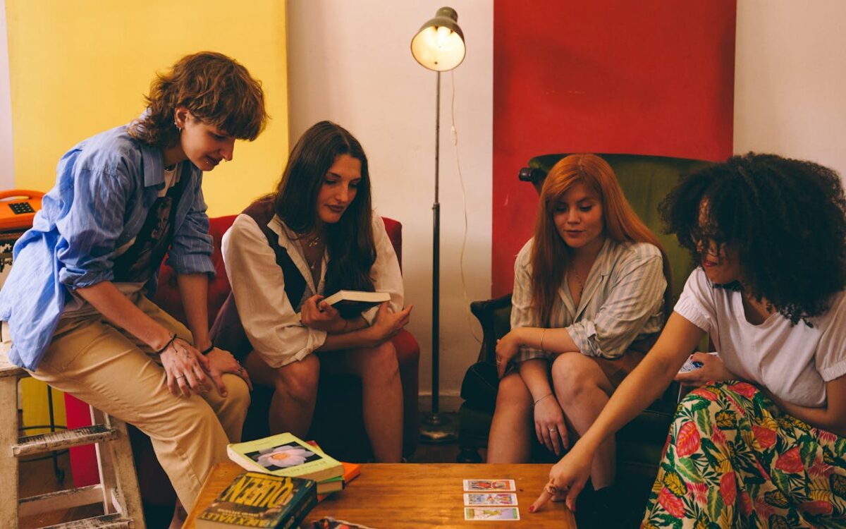 Four adults engaging in a tarot card reading session in a cozy, colorful room.