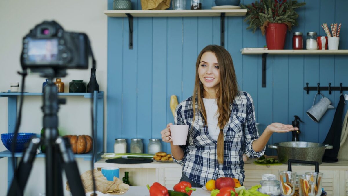 Young woman filming a cooking vlog in a modern kitchen, sharing recipes and tips.