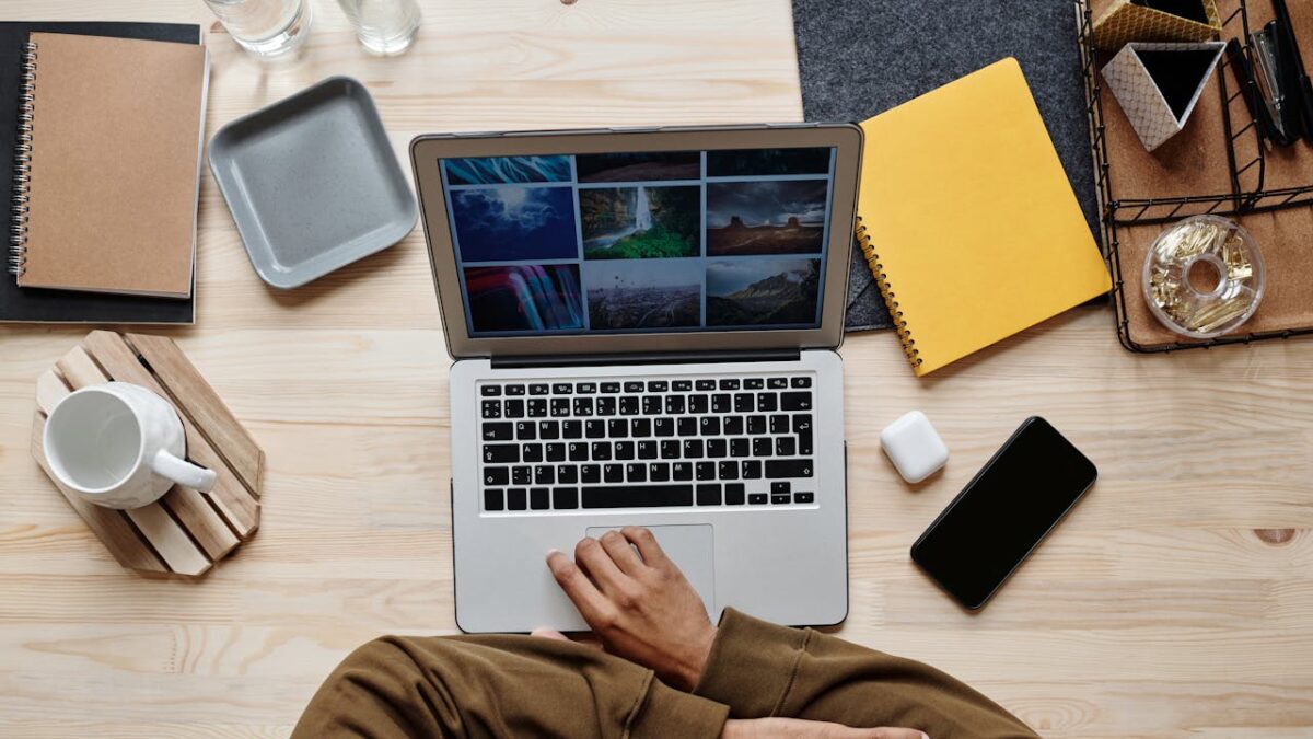 Overhead view of a creative desk setup with a laptop, smartphone, and other office accessories.