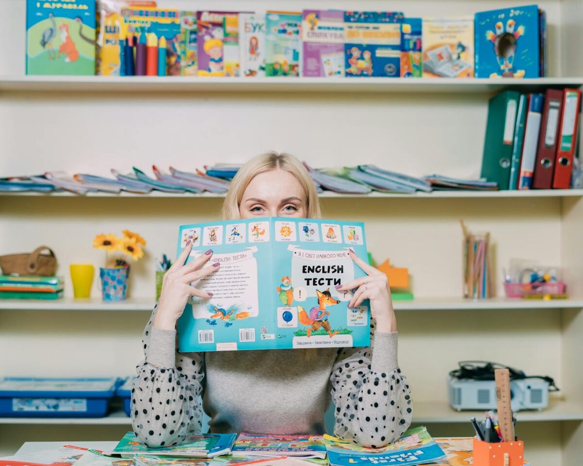 Woman reading an English book in a colorful classroom setting.